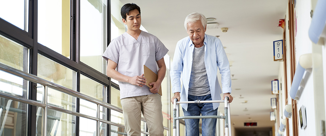 Physical therapist walking with a patient using a walker down a hallway